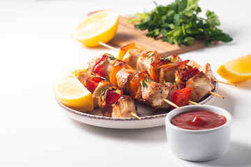 Delicious grilled chicken skewers with capsicum, lemon, salad and ketchup on a plate over the table. Chicken kebab. Healthy food concept.