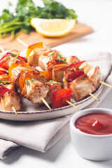 Delicious grilled chicken skewers with capsicum, lemon, salad and ketchup on a plate over the table. Chicken kebab. Healthy food concept.