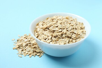 Composition with oatmeal flakes on blue background. Cooking breakfast