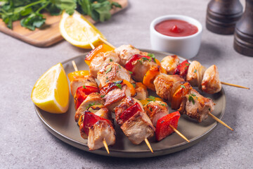 Delicious grilled chicken skewers with capsicum, lemon, salad and ketchup on a plate over the table. Chicken kebab. Healthy food concept.