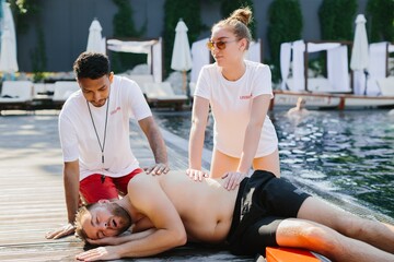 Lifeguards performing cpr on unconscious swimmer by poolside