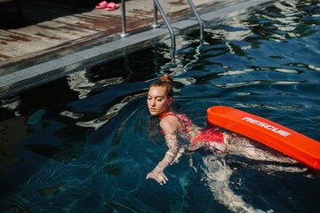 Lifeguard swimming with rescue equipment in pool