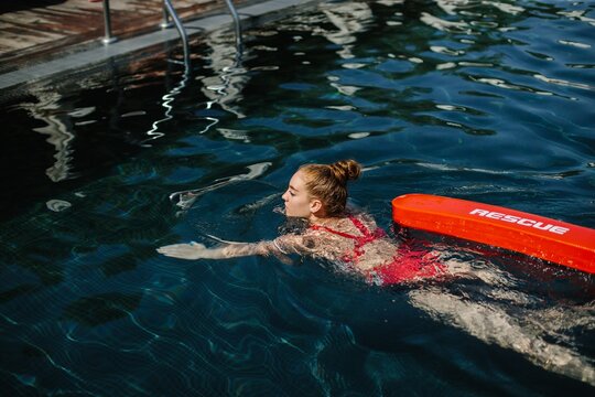 Lifeguard swimming with rescue equipment in pool