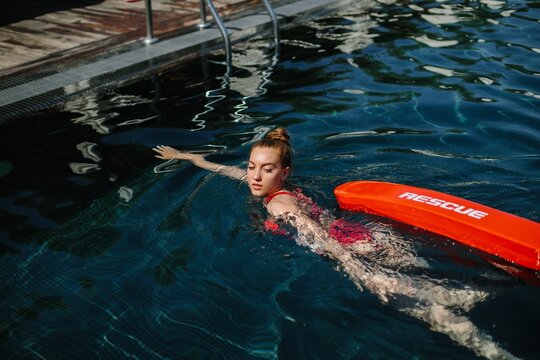 Lifeguard swimming with rescue equipment in pool during training exercise
