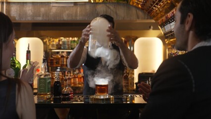 Smart bartender opening mist of whiskey mixed smokey cocktail glass making special drink list presentation for advertisement in focusing alcohol refreshing showcase at luxurious counter bar. Vinosity.
