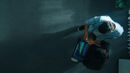 Top down view of manager walking to investor while holding tablet and looking at financial...