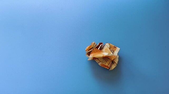 Single crumpled two hundred indian rupee currency bank note falling on blue table background. Extreme closeup top view. India inflation, money devaluation and bad economy creative concept.