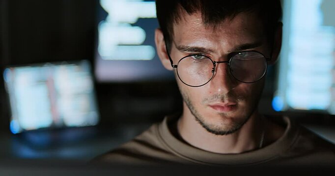 White Caucasian male software developer work late night, program coding in home office. Computer engineering job, data scientist, cybersecurity, information technology. Close-up eyeglasses, handheld