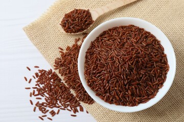 Raw brown rice in wooden bowl on white background. Top view