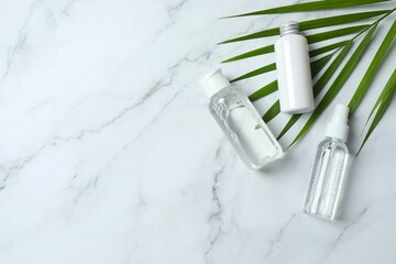 Natural cosmetic products. Cosmetic bottles with palm leaves on a marble background, space for text