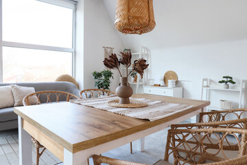 Interior of light dining room with table, sofa and shelf units