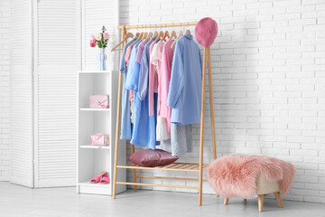 Interior of light dressing room with clothes rack, shelving unit and folding screen