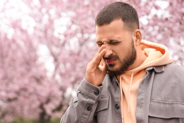 Sick young man suffering from allergy outdoors