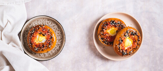 Egg with tomato and sesame seeds baked in bagels on a plate top view web banner