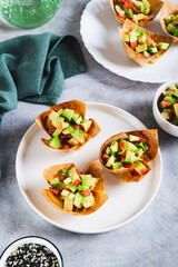 Mini baked pita cups with guacamole on a plate on a table vertical view