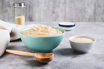 Sesame tahini in a bowl and sesame seeds in a bowl on the table