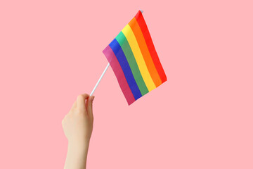 Female hand with LGBT flag on pink background