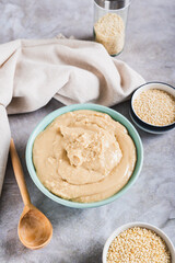 Homemade sesame tahini in bowl on grey table vertical view