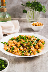 Warm salad of white fried beans and parsley on a plate on the table vertical view