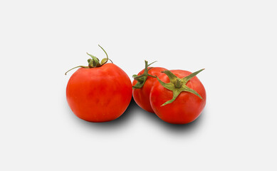 three vine-ripened red tomatoes evenly spaced side by side on a seamless white background. Soft overhead lighting accentuates the taut glossy skins, vibrant color saturation, and slender green stem