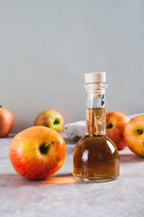 Apple cider vinegar in a bottle and fresh apples on the table vertical view