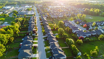 Obraz premium Aerial view of suburban neighborhood showcasing rows of houses with lush green trees and sunset