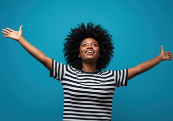 Smiling black woman with open arms looks up with joy and happiness.