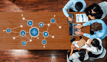 A diverse business team engages in strategic planning and data analysis using modern tools, highlighting global connectivity and collaboration in a contemporary workspace. Amity