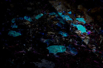 Dimly lit abstract composition featuring clusters of glowing turquoise stones and deep surrounding darkness. The layout mimics subterranean mineral deposits glowing faintly beneath a rough, uneven