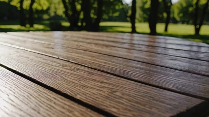 Sunlit outdoor wooden table in natural park setting with lush greenery in summer