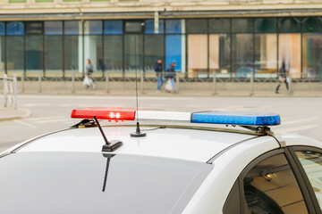 red and blue flashing light on a police car and out of focus pedestrians walking on the sidewalk in front of it. selected focus