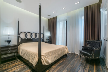 Gothic style in the interior design of the bedroom with a panoramic window. Black furniture. Four...
