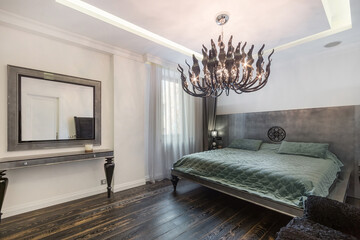 A bedroom in a luxury apartment with an exclusive interior design. A delightful chandelier. Stylish furniture.