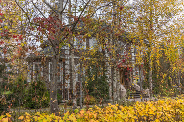 Naklejka premium A private house surrounded by trees in the decoration of golden autumn. An atmosphere of calm.