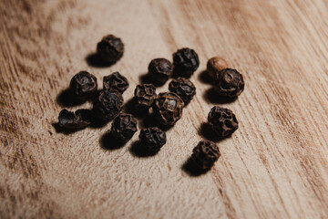 Close-up of aromatic black peppercorns on a wooden surface in warm lighting