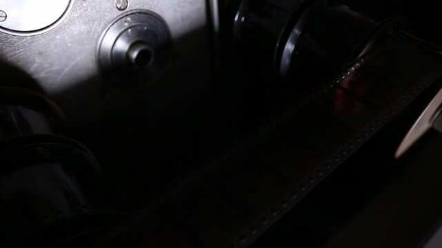  Macro shot: Vintage film strips glide through intricate projector or scanner rollers. Evokes cinema nostalgia and analog processes. Perfect for archival, retro, or filmmaking themes.
