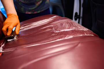 Cleaning a Luxury Car Seat with a Detail Brush and Foam for Maintaining Its Appearance
