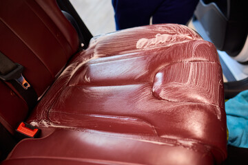 Cleaning a Luxury Car Seat with a Detail Brush and Foam for Maintaining Its Appearance