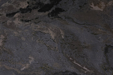 Dark textured stone surface resembling rugged rock with natural earthy tones and irregular mineral patterns. Suitable for geology-related themes, architectural material catalogs, and textured