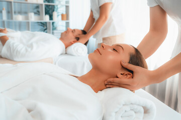 Fototapeta premium Caucasian couple enjoying relaxing anti-stress head massage and pampering facial beauty skin recreation leisure in dayspa modern light ambient at luxury resort or hotel spa salon. Quiescent