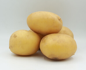 Clean composition featuring three whole yellow potatoes on a seamless white surface. The organic shape and earthy tones highlight their natural simplicity, ideal for food-related content such as healt