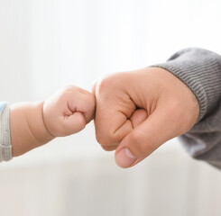 Big and little men connection. Father and baby son bumping fists, closeup