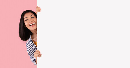 Intresting Offer. Happy Casual Asian Woman Peeping Out The Side Of White Advertisement Board For...