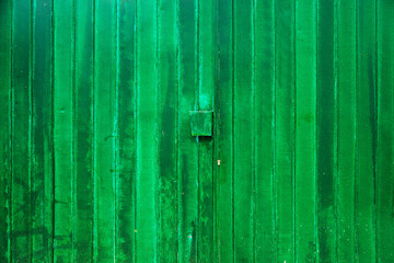 Old green worn metallic garage door as grunge background