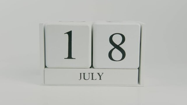 A hand flips a wooden calendar from July 18th to July 19th on a white background, signaling a shift to a new day