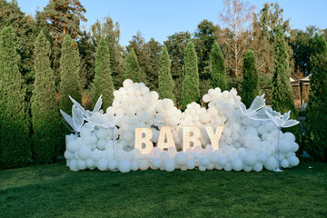 An outdoor baby shower decoration with white balloons, large illuminated 