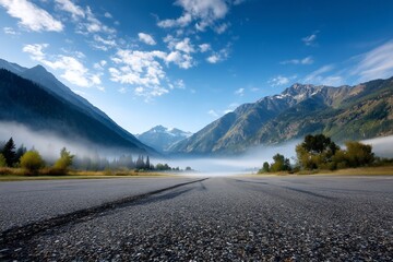 Road leads to misty mountain peaks under a bright blue sky. Nature background