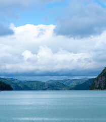 Serene lake surrounded by lush mountains.