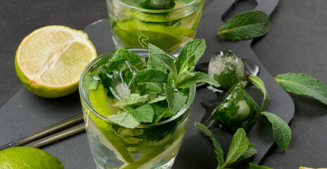 Refreshing mojito cocktail with lime, mint, strawberry, and ice on dark background, top view