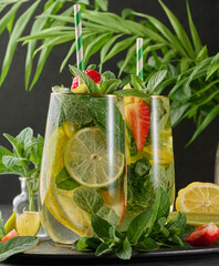 A refreshing drink in a glass with lemon slices, strawberries, fresh mint leaves, and sparkling...
